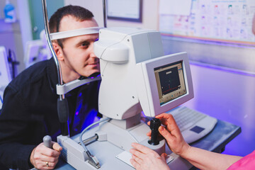 A young man at an oculist's appointment checks his vision with a modern microscope.