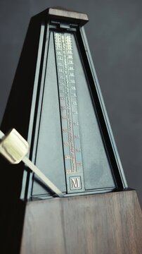 Vertical shot of metronome pendulum is shown at different positions. Helpful for timing, rhythm, and tempo in music practice