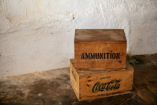 Two old wood boxes stacked on each other, one with CocaCola logo on it and the other saying "ammunition" inside a national park exhibit at Castillo San Felipe del Morro, San Juan, Puerto Rico