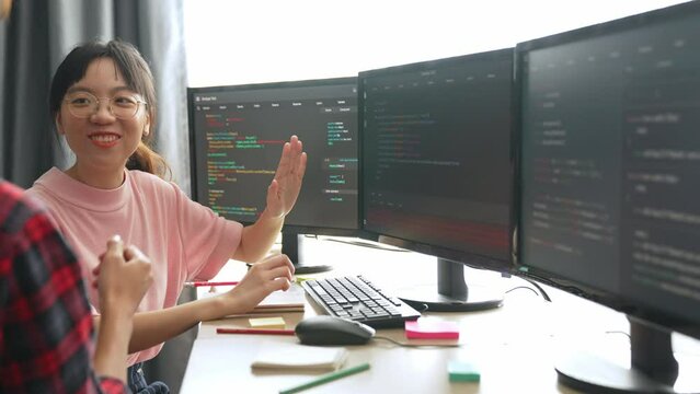 Slow motion back end software developer engineer for computer programming working together on debugging writing computing code, solving complex algorithms display on monitor in office. Burgeoning