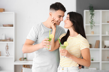 Happy young couple with glasses of mojito at home
