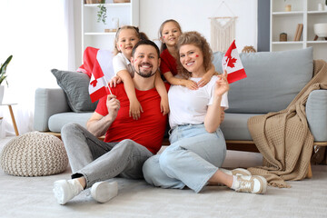 Happy family with flags of Canada sitting on floor at home