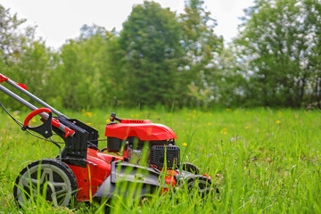 lawn mower in the garden in summer on the grass.