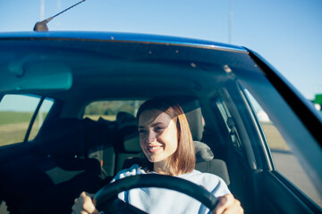 positive young woman driver driving in summer