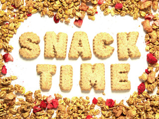 Word snack time with letters made from cookie on white background framed by granola cereal with...