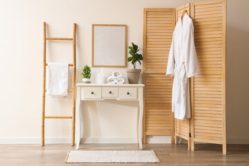 Interior of modern stylish bathroom with commode and hanging bathrobe