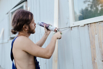 a male master installs windows with polyurethane foam in a residential building.