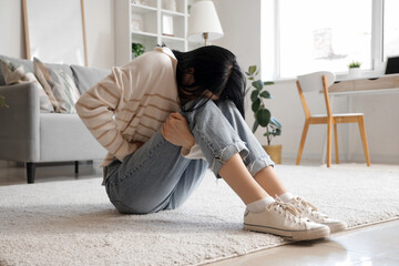 Young woman suffering from severe abdominal pain at home
