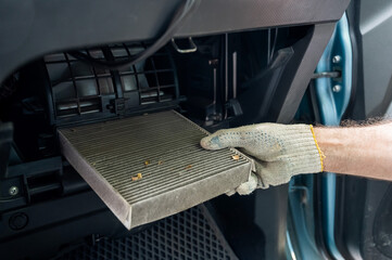 A mechanic changes the cabin air filter of a car.