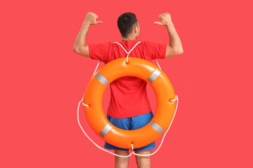 Handsome male lifeguard with ring buoy on red background, back view