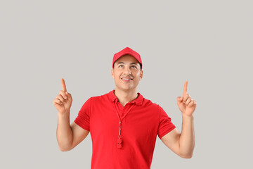 Happy male lifeguard pointing at something on grey background