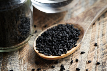 Black cumin or Nigella sativa seeds on a spoon. Nutritional supplement.