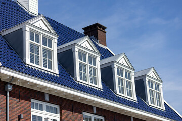 Architectural detail of typical Dutch bright colored deep blue rooftop with window panes