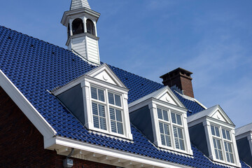 Architectural detail of typical Dutch bright colored deep blue rooftop with window panes