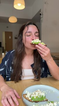 Woman enjoying avo toast during coffee break in a calm cafe