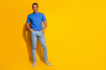 Fototapeta premium Full body photo of attractive young man posing model hands pockets dressed stylish blue clothes isolated on yellow color background