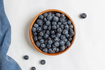 A wooden bowl filled with fresh blueberries, view from above.