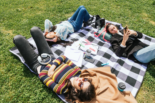 Three college friends studying and relaxing outdoors