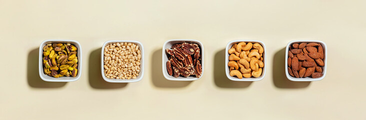 Various types of dry nuts in a small bowls, overhead view. Healthy fat, essential nutrient