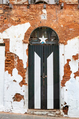 Large weathered black and white door on facade of old abandoned government brick building in Old San Juan, Puerto Rico