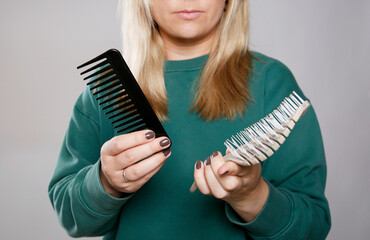 Caucasian woman with blond hair deciding to choose between a brush or a comb. Healthy hair concept 