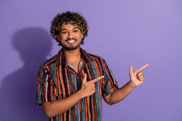 Portrait of nice young man direct fingers empty space wear shirt isolated on purple color background