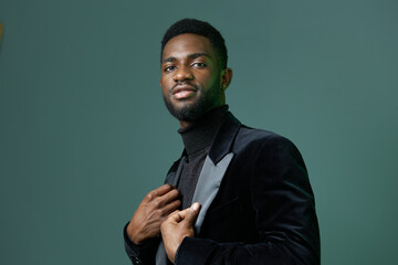 Fototapeta premium Stylish man in sleek black attire confidently poses against a vibrant green wall background