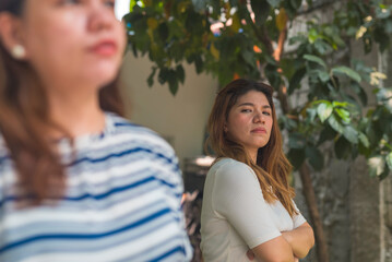 A woman intensely scrutinizes another woman with a jealous expression outdoors. Giving the side...