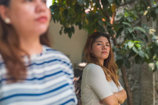 A woman intensely scrutinizes another woman with a jealous expression outdoors. Giving the side eye. Depicts rivalry, suspicion, and interpersonal conflict.