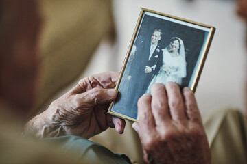 Senior man, hands and vintage photo for memory in home, retirement and nostalgia for mourning. Male person, picture and remember in living room, history and grief on past life or retro wedding image
