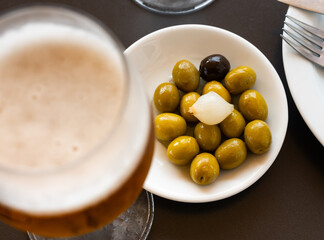 Appetites are waiting on table, light snack - bowl with pickled green olives and garlic,...