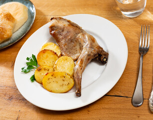 Rabbit thigh, stewed with potatoes and spices. Hearty homemade dinner served with light white sauce and bran bread. Rabbit meat baked until golden brown with potato segment