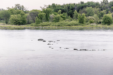 A scenic lake shoreline with rocky terrain and trees in the background