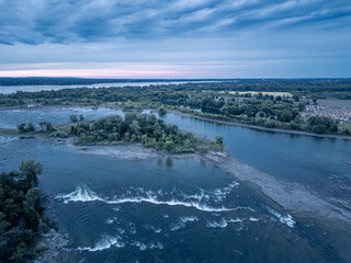 A scenic lake shoreline with rocky terrain and trees in the background