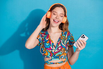 Portrait of lovely young girl headphones smart phone wear top isolated on blue color background