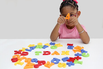 4 year old Latina brunette girl plays with colored letters and forms the word TDAH which means attention deficit hyperactivity disorder in spanish