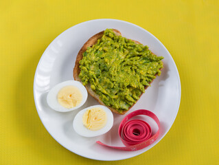 Food for weight loss. Egg, avocado, toast, meter. Cooking healthy food at home. Food on a yellow background.