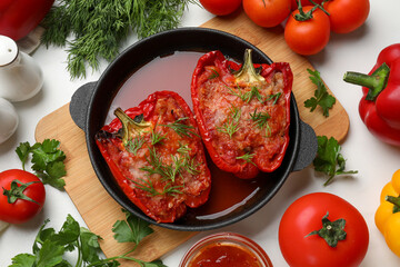Tasty stuffed peppers in dish and ingredients on white table, flat lay