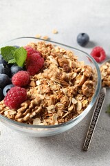 Tasty granola with berries, nuts and mint on grey table