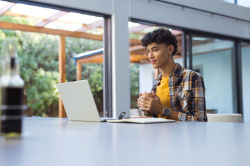 Using laptop, teenage boy with notebook studying at home, focusing on work, copy space