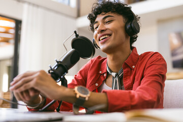 Recording podcast, teenage boy speaking into microphone wearing headphones