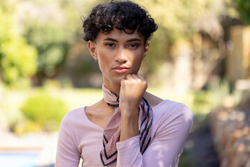 Posing confidently, transgender transgender woman standing outdoors with hand on chin