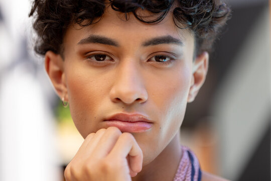 Close-up of thoughtful transgender transgender woman resting chin on hand, looking pensive