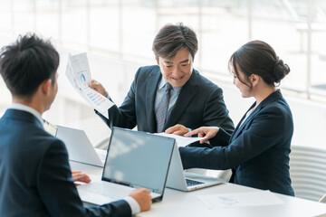 Fototapeta premium 企業のオフィスで笑顔で会議・ミーティング・商談をするアジア人ビジネスマンとビジネスウーマン 