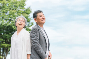 公園で空を見上げるシニア・高齢者夫婦（笑顔）
