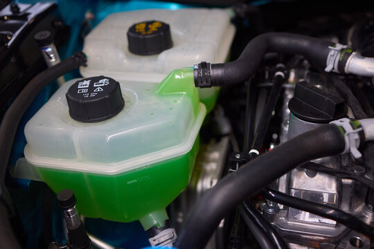 Get a closer look at the coolant reservoir of a car, situated in the engine compartment