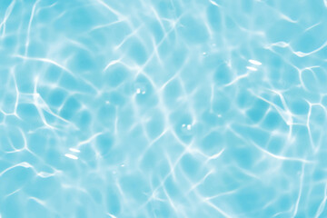Blue water with ripples on the surface. Defocus blurred transparent blue colored clear calm water surface texture with splashes and bubbles. Water waves with shining pattern texture background.