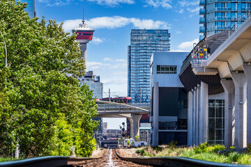 Low rail view of Canadian Pacific tracks entering downtown next to elevated transit platform overlooking popular landmarks in Calgary Alberta Canada.
