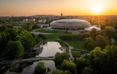 Huge park (Polish Aviators Park) with small lake in Krakow with colorful trees and round stadium during spring sunset.
