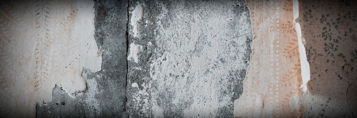 Torn old faded paper wallpaper with a retro pattern. Tattered scraps of paper on a concrete wall. Vintage texture for background and design. Closeup view with copy space.
